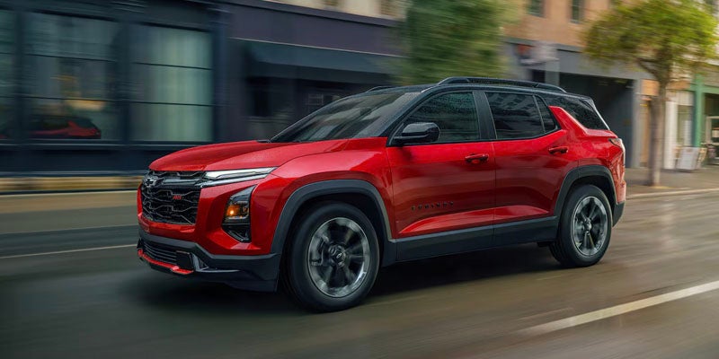 A photo of a red 2025 Chevy Equinox driving down a city street