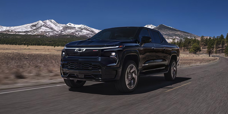 A black 2025 Chevy Silverado EV driving down a highway