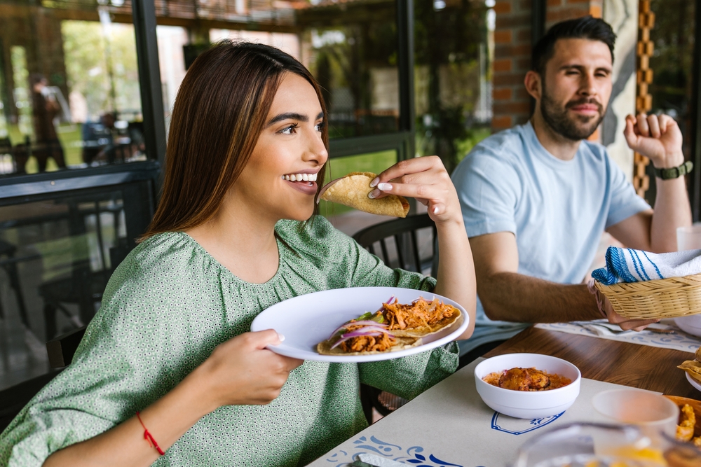 A man and woman eating tacos.